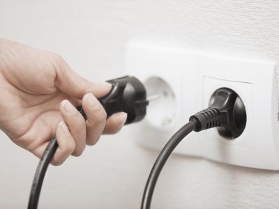 Woman pluging cable to the electric outlet