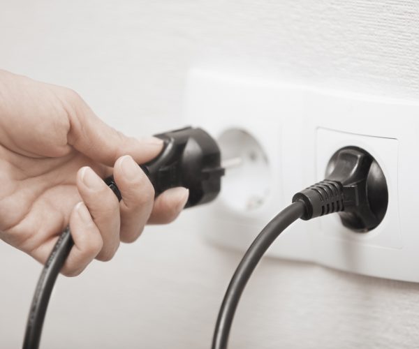 Woman pluging cable to the electric outlet